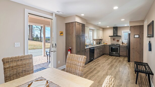 A modern kitchen with wooden cabinets, a dining area with wicker chairs, and a view of the outdoors.