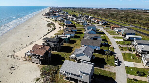 A coastal residential area with houses along the beach, a road, and a clear view of the ocean. - Under the Sea (Galveston)