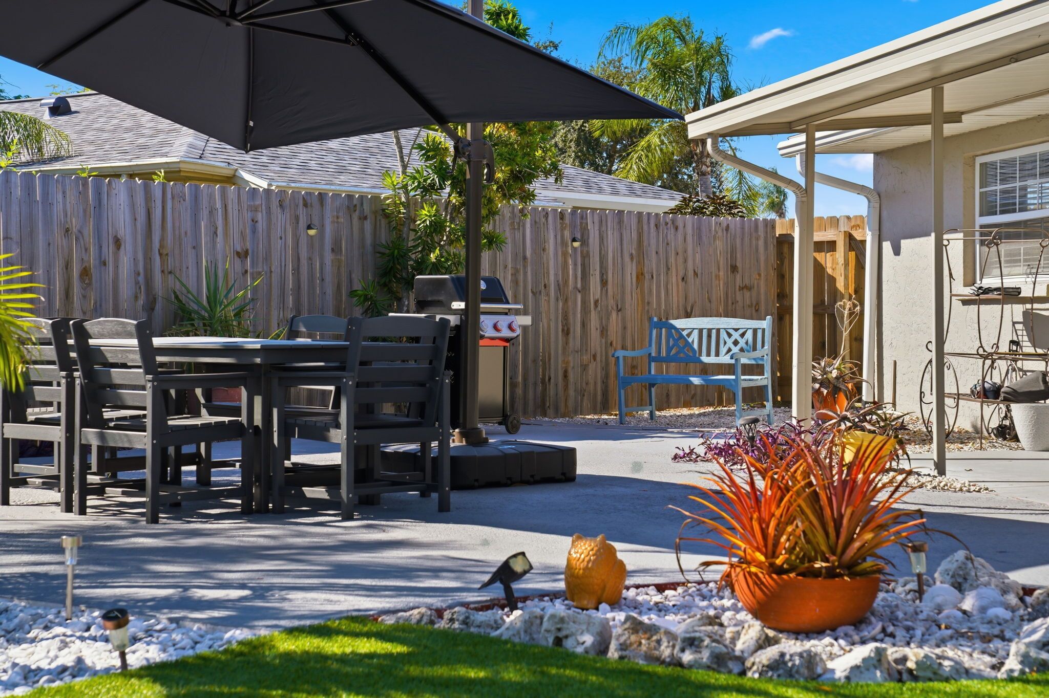 A patio area with a table and chairs, a barbecue grill, and a covered seating area.