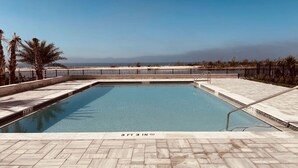 Une piscine rectangulaire à l’eau d’un bleu limpide, entourée d’une terrasse carrelée.