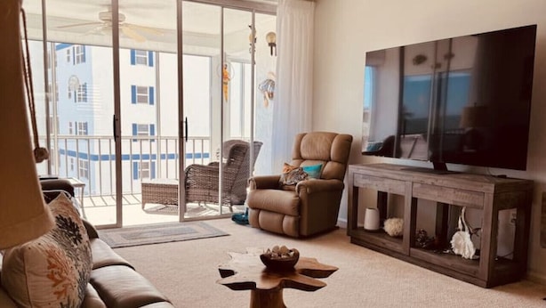 Un salon comprenant un canapé, une table basse, un téléviseur et un ventilateur de plafond.