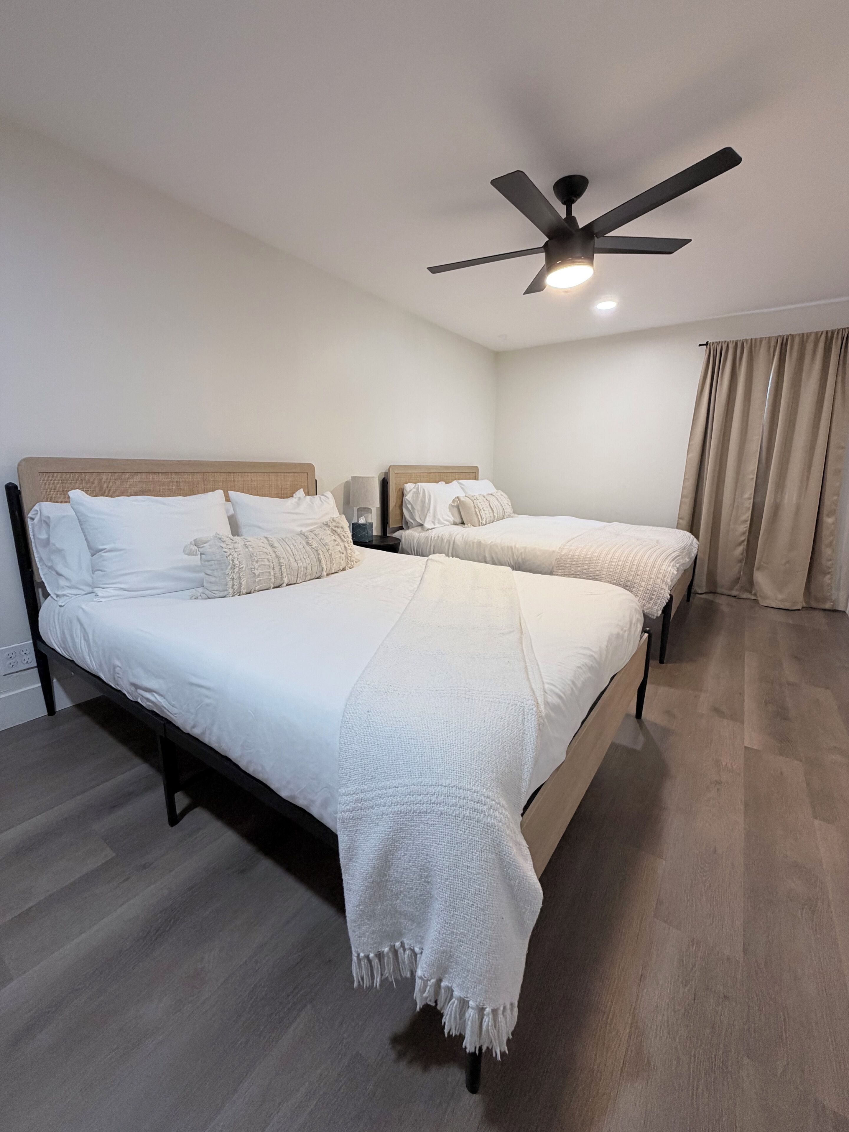 Un dormitorio con dos camas, un ventilador de techo y una mesita de noche.