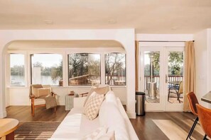 Amplia sala de estar con un sofá grande, una mesa de centro y vistas a un lago a través de amplios ventanales.