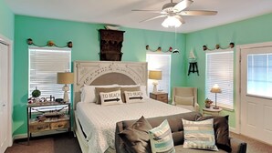 A bedroom with a bed, a chair, a desk, and a ceiling fan. - Coral Cabana (Port Aransas)