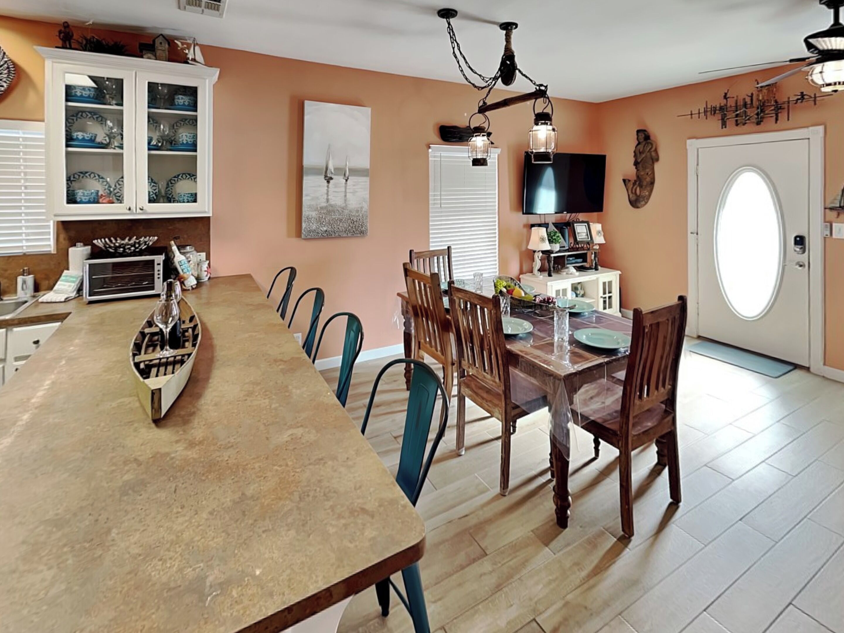 A dining area with a long table, chairs, a chandelier, and a television.