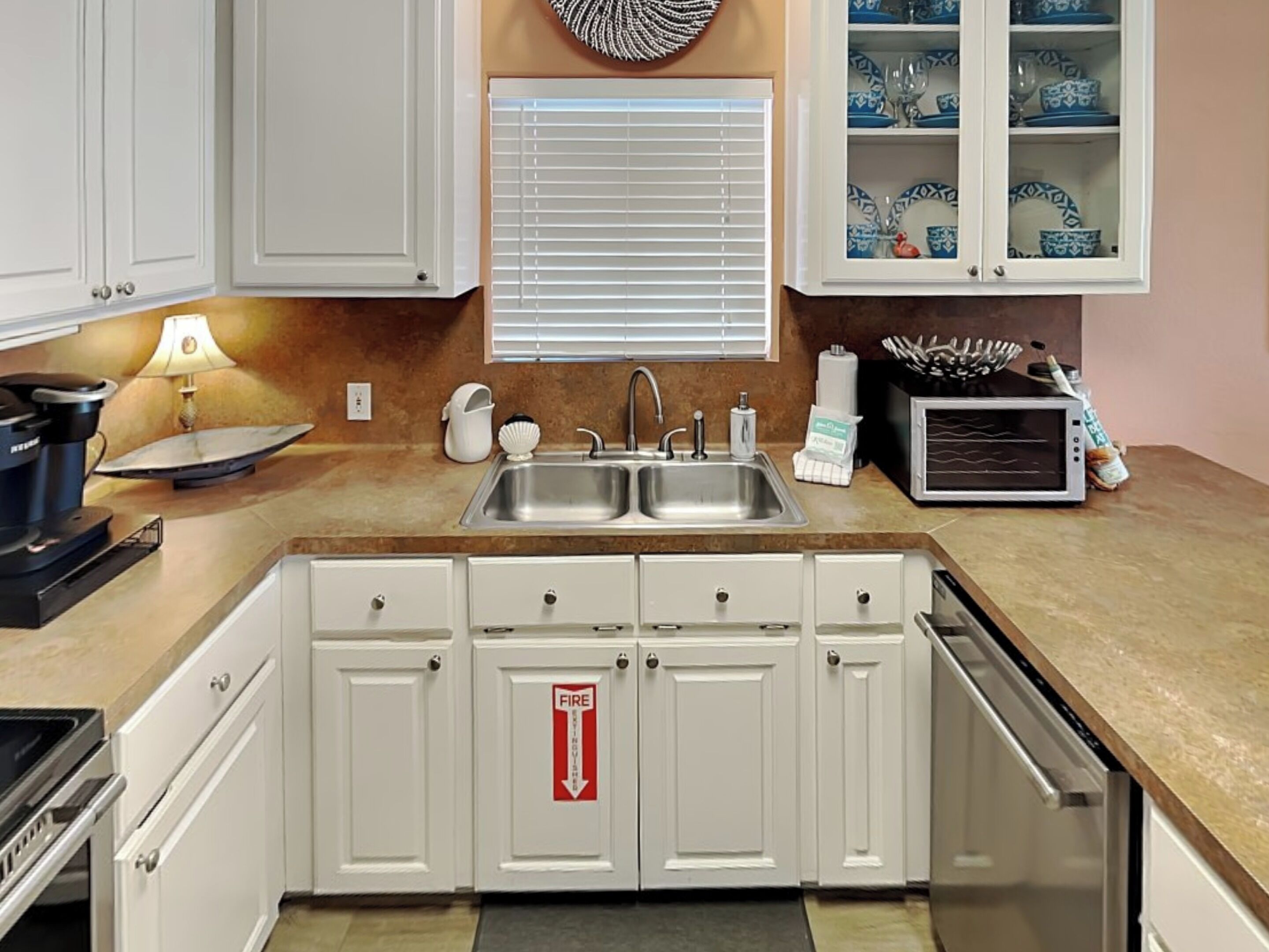 A kitchen with white cabinets, a double sink, a stove, and a microwave.