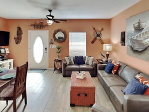 A living room with a brown leather sofa, a coffee table, and a dining area with a wooden table and chairs.