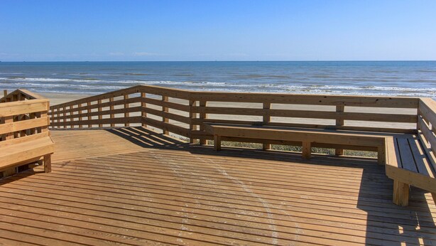 A wooden deck with a railing overlooking the ocean. - Coral Cabana (Port Aransas)