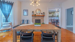 A dining room with a wooden table, black chairs, a fireplace, and a chandelier. - Soul of SoHa, a spacious 5-bedroom retreat in South Haven, MI. (South Haven)