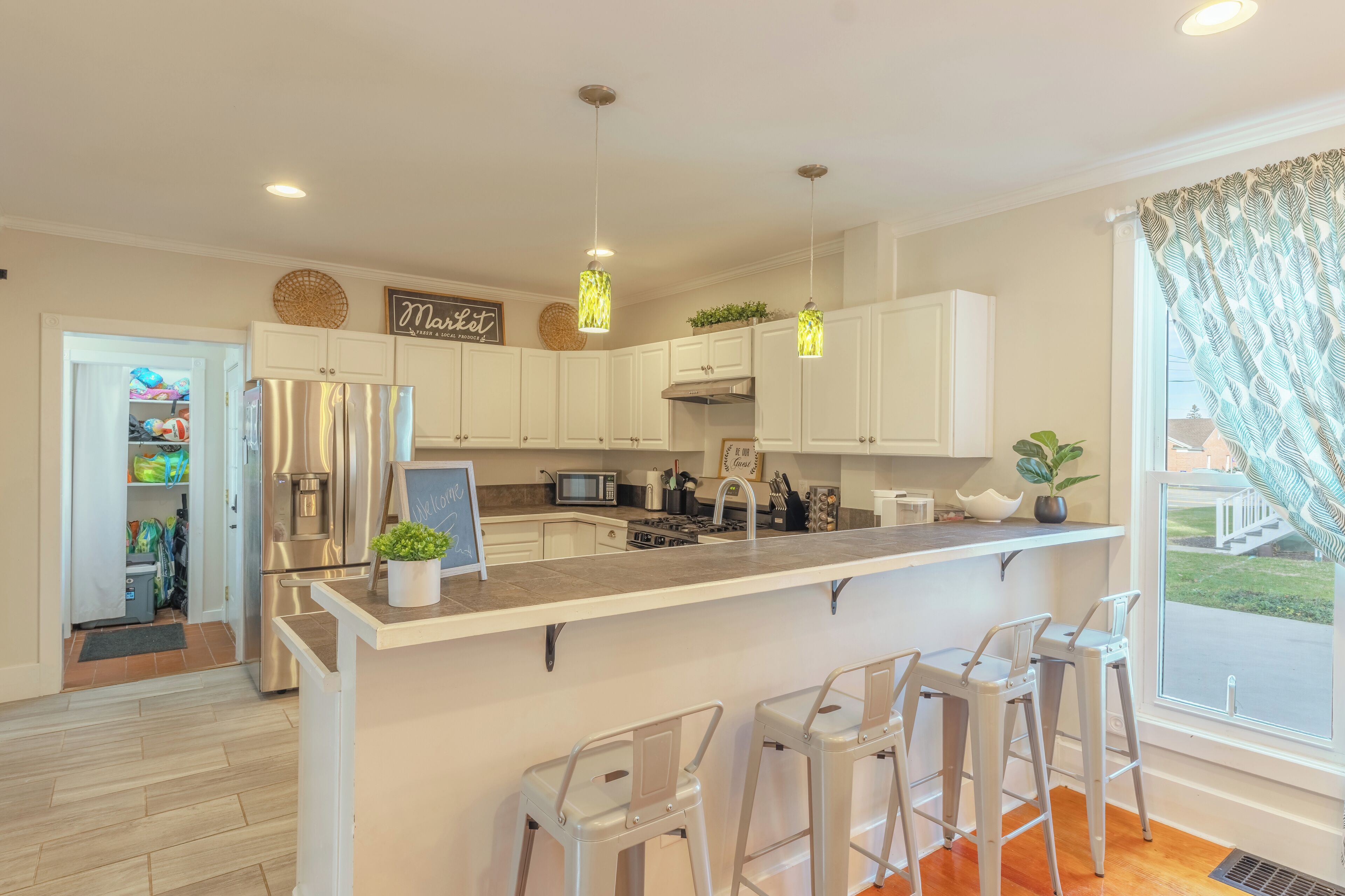 Una cocina moderna con armarios blancos, electrodomésticos de acero inoxidable y una isla central con taburetes de bar.