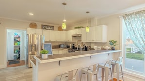 A modern kitchen with white cabinets, stainless steel appliances, and a central island with bar stools. - Soul of SoHa, a spacious 5-bedroom retreat in South Haven, MI. (South Haven)