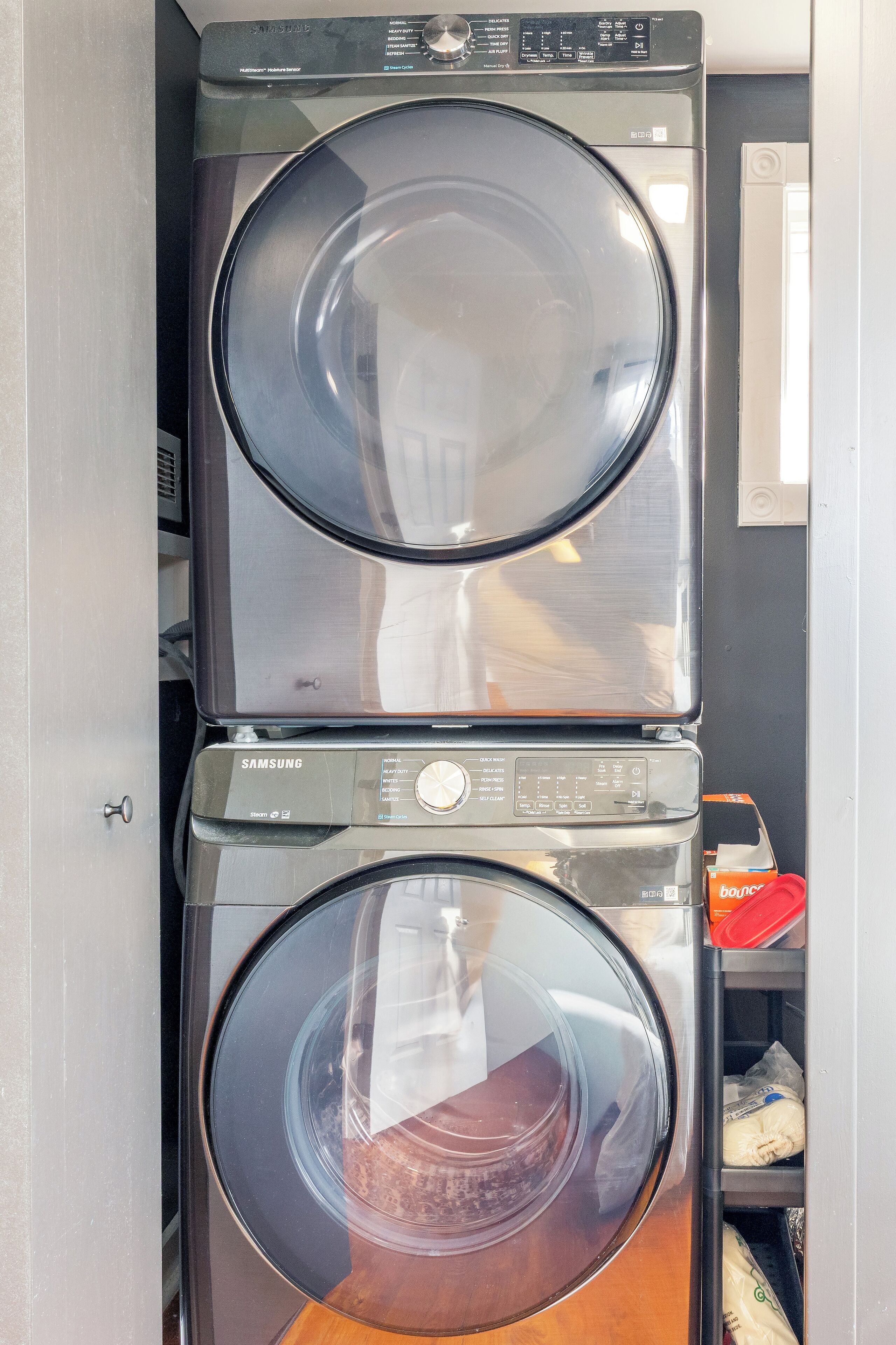 A stacked washer and dryer unit with a control panel and a small shelf with items.