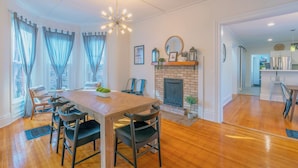 A dining area with a wooden table and chairs, a fireplace, and a view of the city through large windows. - Soul of SoHa, a spacious 5-bedroom retreat in South Haven, MI. (South Haven)
