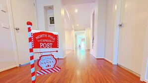 Um corredor com um poste listrado de vermelho e branco, identificado como 'Correio Expresso do Polo Norte', e uma placa com a inscrição 'Cartas para o Pai Natal'.