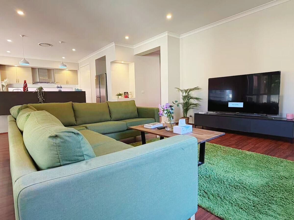 A modern living room with a sectional sofa, a flat-screen TV, and a small coffee table.