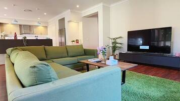 A modern living room with a sectional sofa, a flat-screen TV, and a small coffee table.