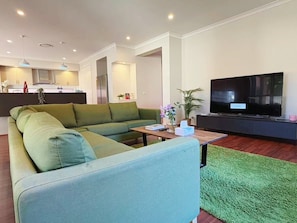A modern living room with a sectional sofa, a flat-screen TV, and a small coffee table.
