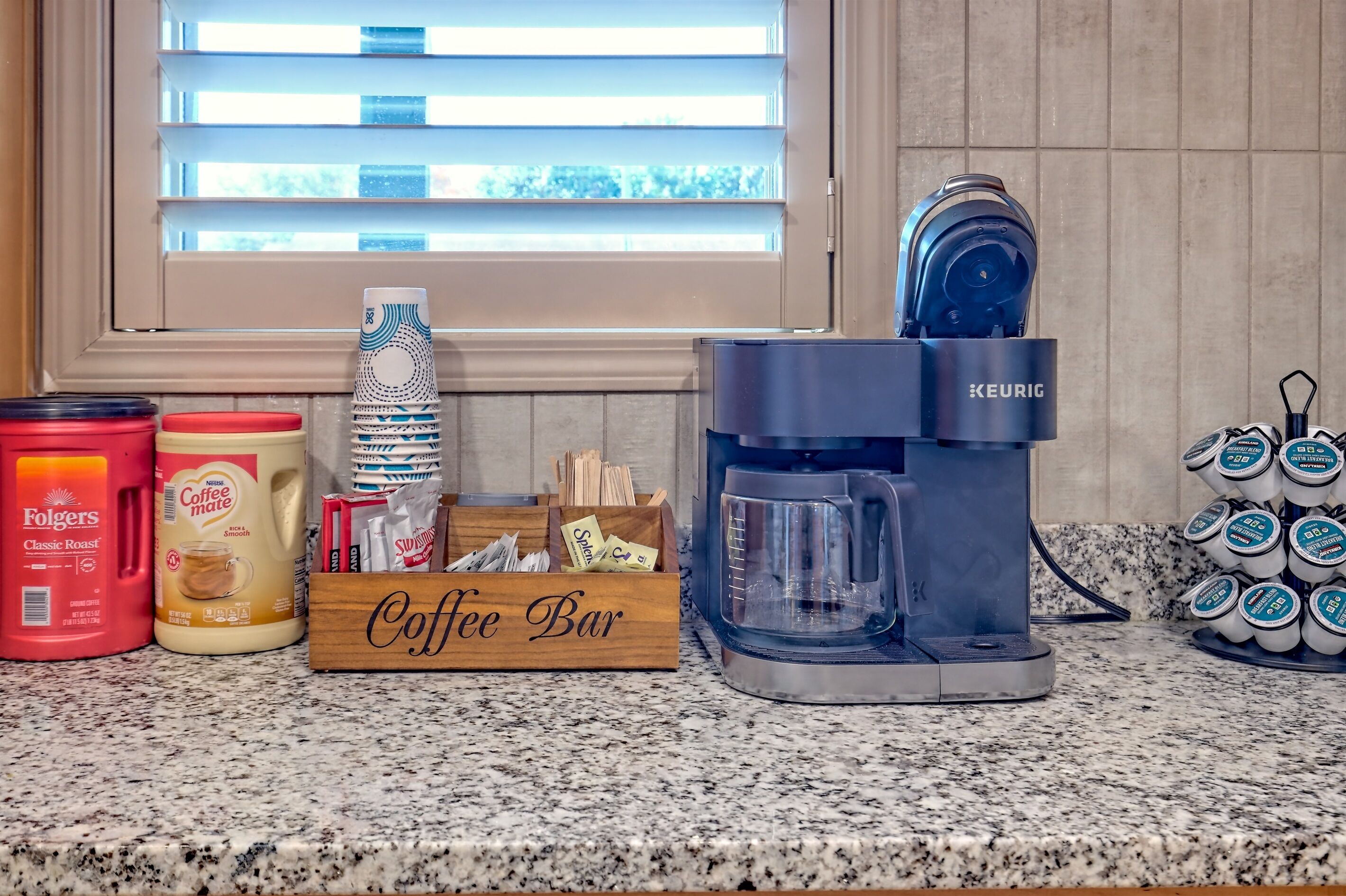 A coffee bar setup with a Keurig coffee maker, Folgers coffee, and a coffee mug.