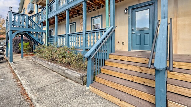 A building with a wooden staircase and blue railings leading to a door marked "105". - Heart of Helen - 1st Floor | Walk to Main Square (Helen)