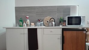 A kitchen with a microwave, a kettle, and various kitchen items on the counter. - Maison Villa Torlonia (Rome)