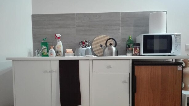 Una cucina con forno a microonde, bollitore e diversi oggetti da cucina sul piano di lavoro.