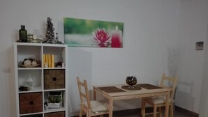 Un'area pranzo con un tavolo e sedie in legno, un mobiletto bianco con diversi oggetti e un quadro con dei fiori sulla parete.