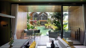 Um interior moderno com área de jantar, sofá e vista para uma piscina e jardim ao ar livre.