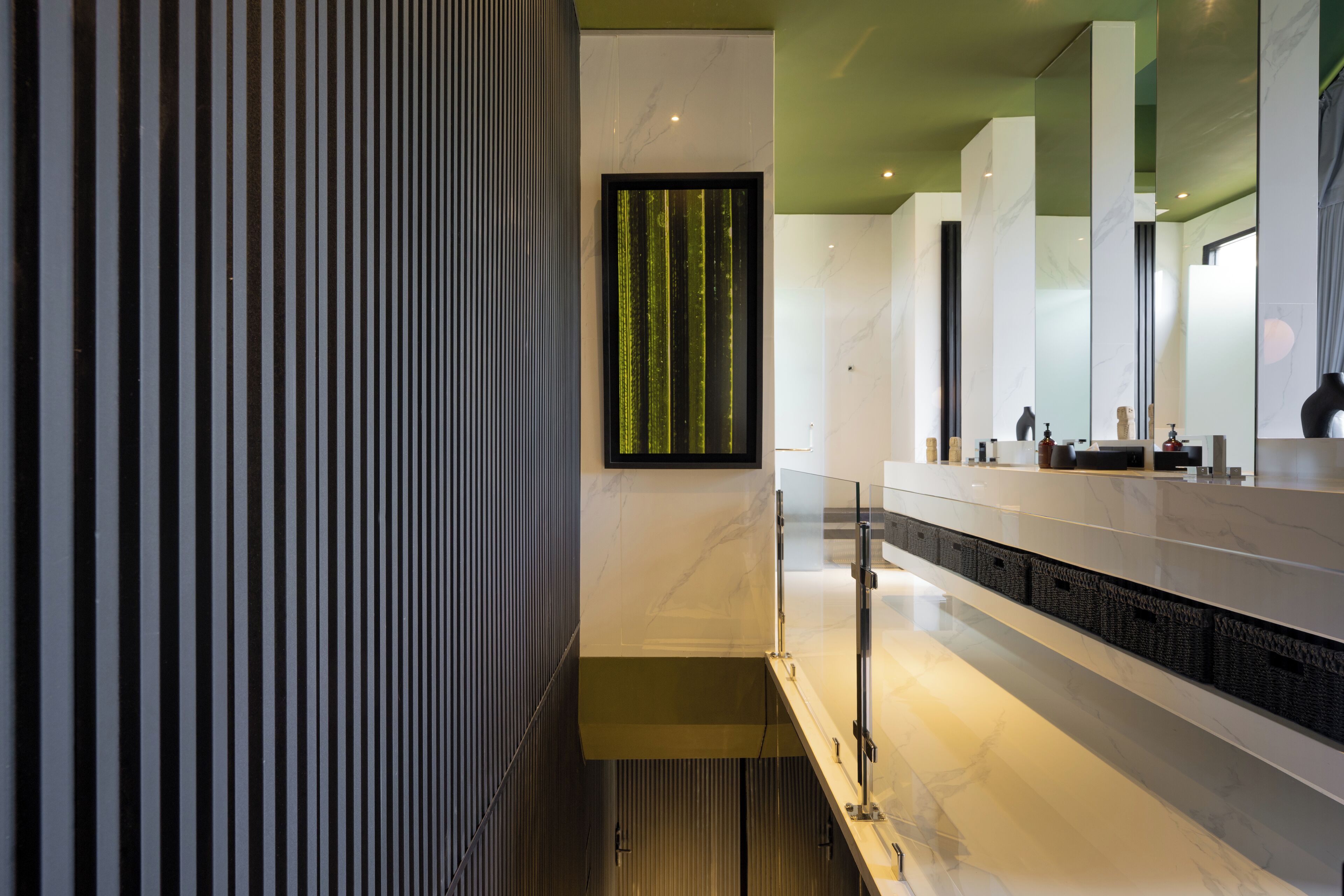 A modern bathroom with a marble countertop, a vertical striped wall, and a green decorative panel.