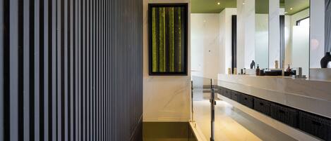 A modern bathroom with a marble countertop, a vertical striped wall, and a green decorative panel.