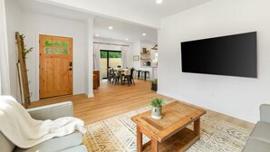 Una sala de estar moderna con una mesa de centro de madera, un sofá gris y un televisor montado en la pared.