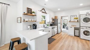 Una cocina moderna con armarios blancos, una isla central y electrodomésticos integrados, incluyendo una lavadora.