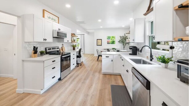 Una cocina moderna con armarios blancos, electrodomésticos de acero inoxidable y una isla central.