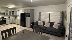 Una cocina moderna con armarios blancos, un refrigerador negro y un comedor con mesa y sillas.