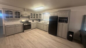 Una cocina con armarios blancos, un refrigerador negro, una estufa y un microondas.