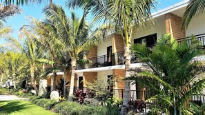 A hotel with multiple floors, outdoor balconies, and lush tropical landscaping. - Bali Hai Beach Resort (Holmes Beach)