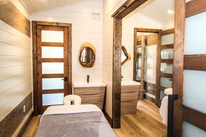 A bathroom with a wooden door, a round mirror, a sink, and a toilet. - Bali Hai Beach Resort (Holmes Beach)