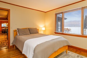 A bedroom with a bed, a nightstand, a lamp, and a window with blinds.