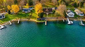 An aerial view of a lakeside property with multiple houses, docks, and a small docked boat.