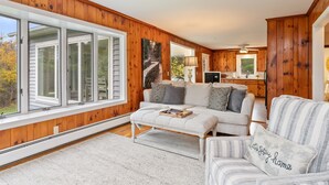 A cozy living room with a large window, a fireplace, and a dining area. - 3 Mins to Watkins Glen | Seneca Wine Trail (Watkins Glen)