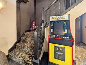 A Pac-Man arcade machine in a hotel lobby with a staircase and a door. - Ozark Cinema & Dance Retreat (Elkins)