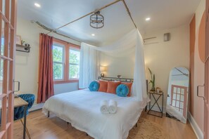 A bedroom with a large bed, a bedside table, a mirror, and a window with curtains. - Luxury 2 Brm: A Zen Den Nestled in the Prestigious Forest Hill Area of Newark NJ (Newark)