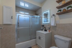 A modern bathroom with a glass-enclosed shower, a white sink with a mirror above it, and a toilet. - Luxury 2 Brm: A Zen Den Nestled in the Prestigious Forest Hill Area of Newark NJ (Newark)