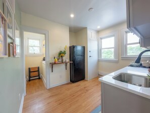 A kitchen with wooden flooring, a black refrigerator, a white sink, and a window with a view of greenery. - Luxury 2 Brm: A Zen Den Nestled in the Prestigious Forest Hill Area of Newark NJ (Newark)