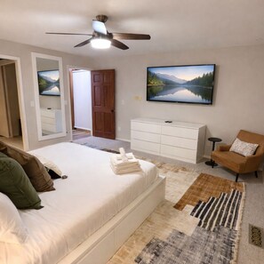 A bedroom with a bed, a dresser, a chair, a television, and a ceiling fan. - Resort-Style Retreat ~ Pool • Hot Tub • Theater • Game Room • Sauna • Acreage  (Arlington)