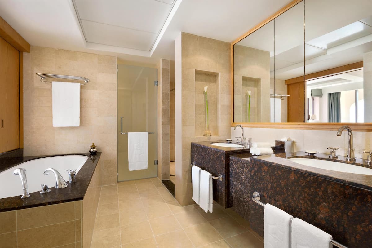 Un baño moderno con una bañera grande, dos lavamanos y un espejo amplio.