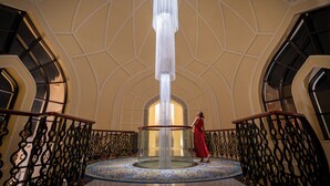 Un interior majestuoso con una columna central, barandillas ornamentales y un suelo con diseños.