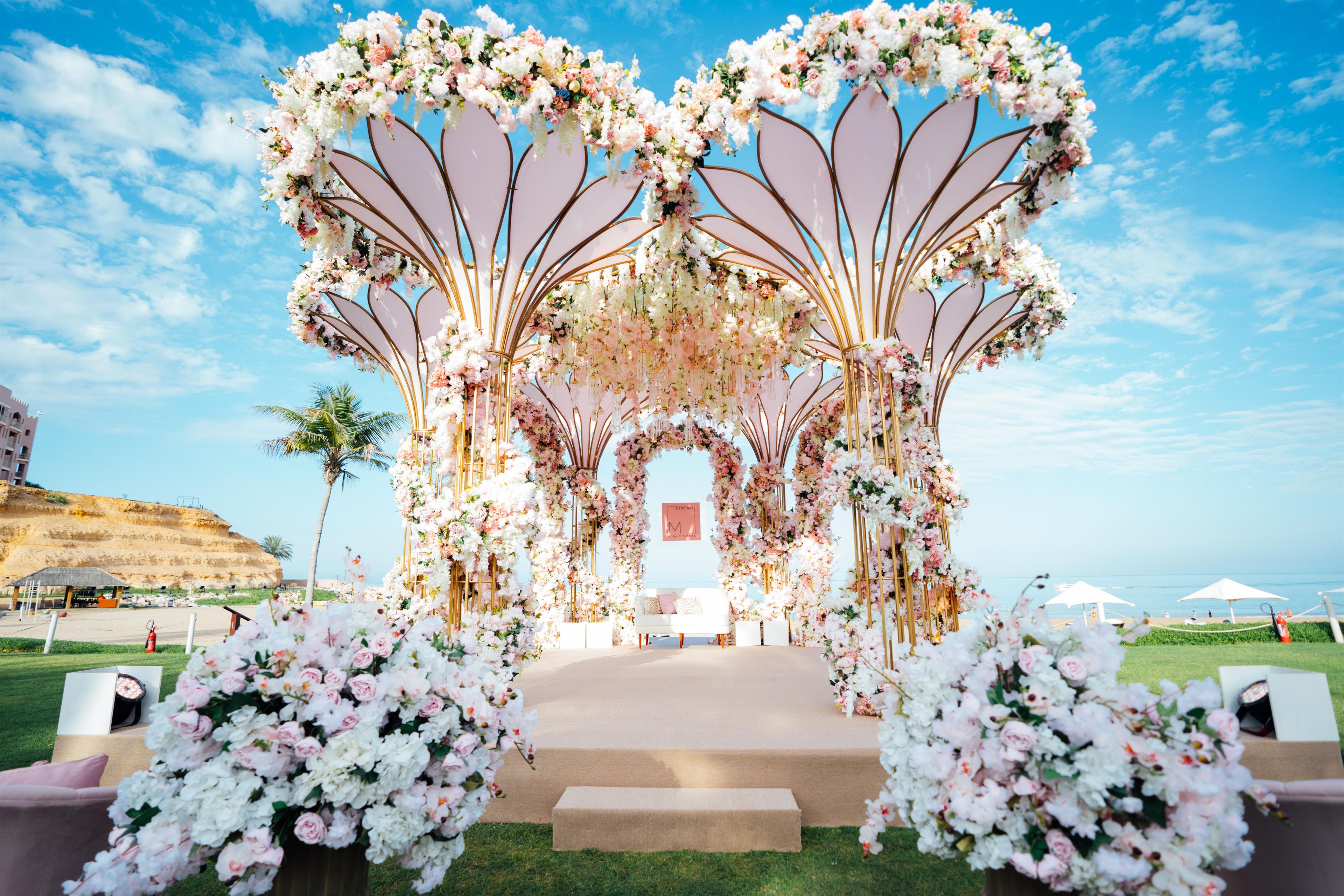 An outdoor wedding arch with floral decorations and a clear sky.