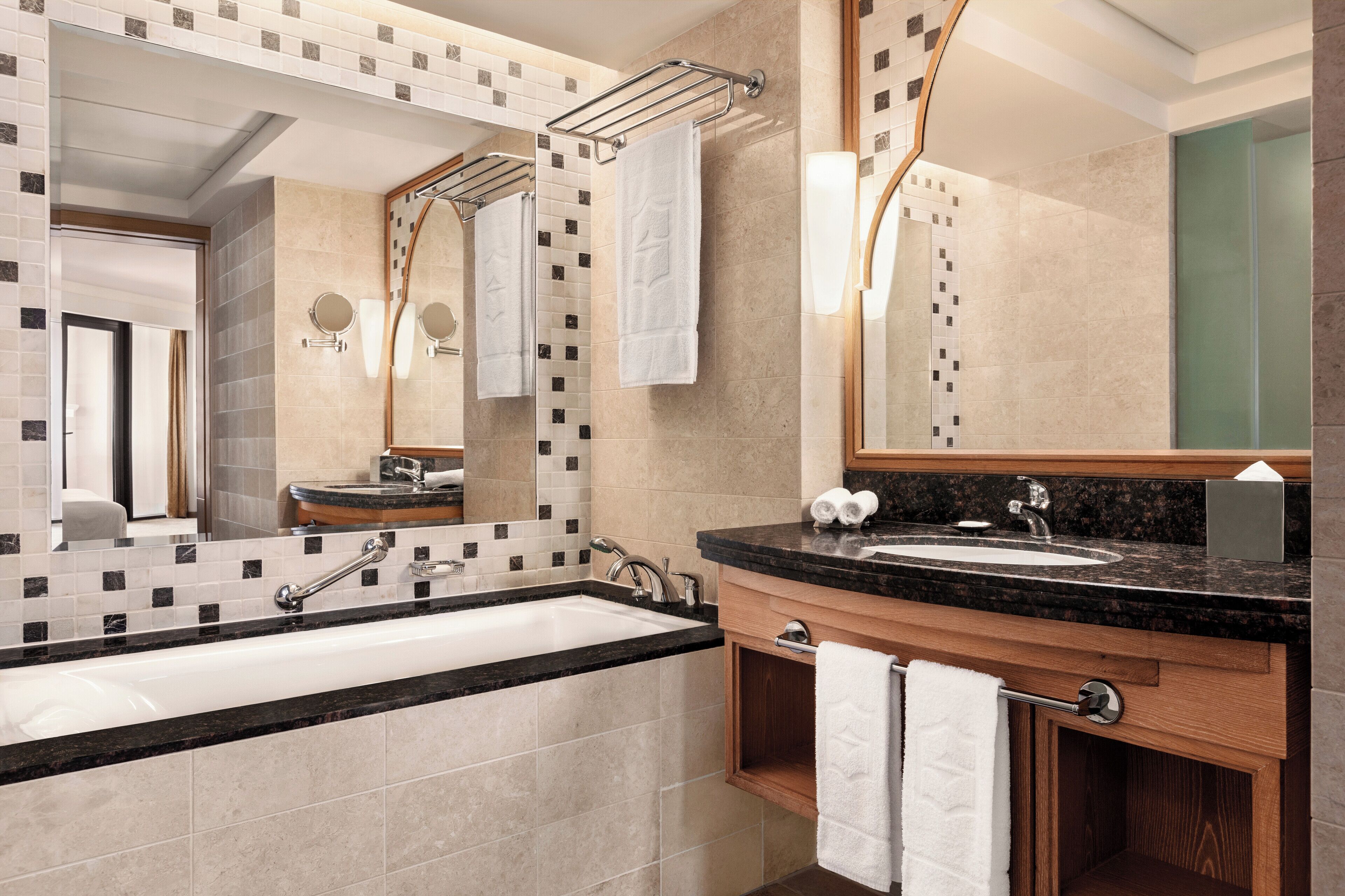 A modern bathroom with a large sink, mirror, and towel rack.