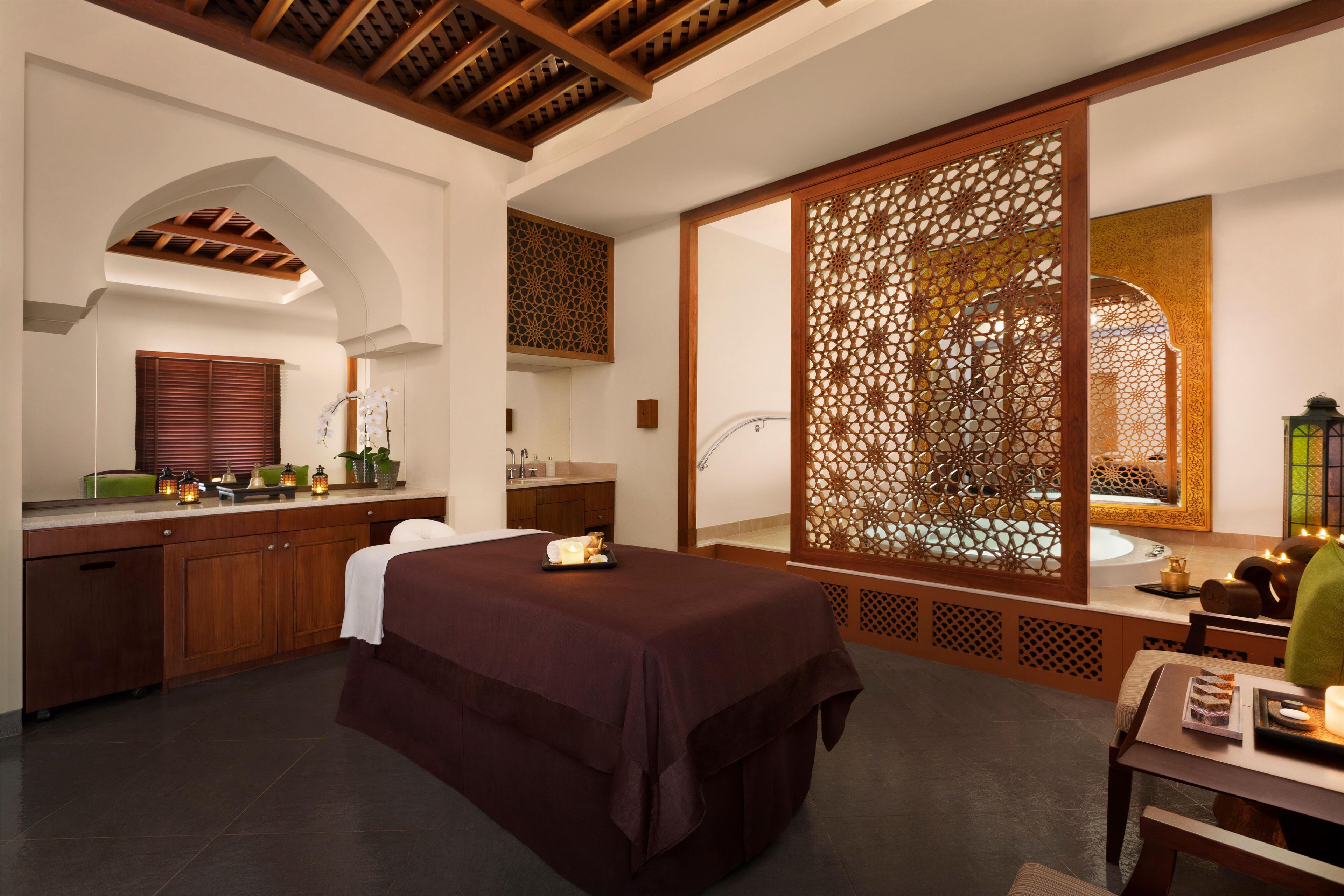 A hotel room with a bed, a bathroom, a wooden ceiling, and a decorative screen.