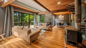 Una sala de estar moderna con un ventanal grande, una chimenea y un comedor.